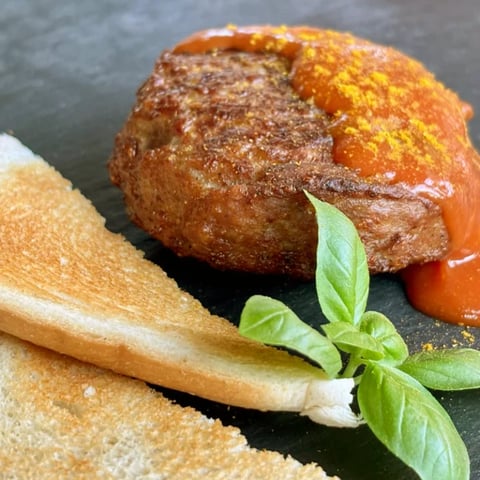 Fried donut coated with cinnamon sugar, served with breadstick and fresh basil on dark plate