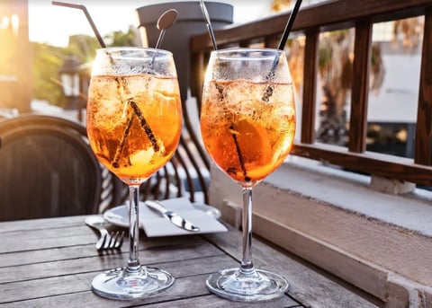 Two glasses of iced tea or cola with straws on a wooden table at an outdoor café during sunset